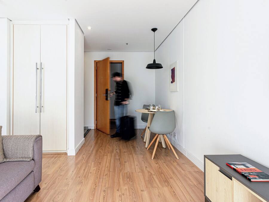 A modern living space with a sofa, a dining table with chairs, and a small cabinet with books.