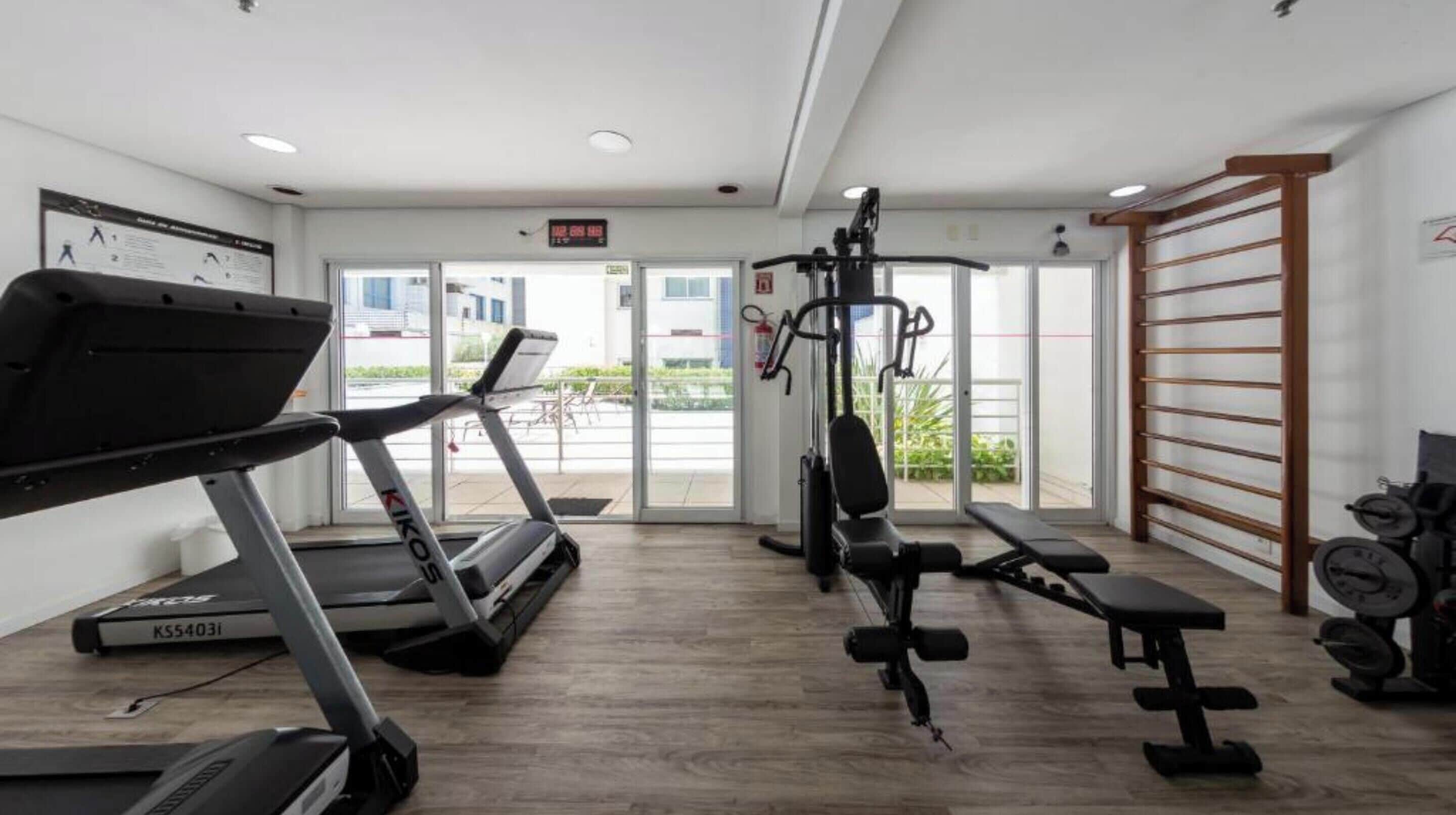 Ein Fitnessraum mit Laufbändern, Gewichteinrichtungen und einem an der Wand befestigten Trainingsgerät.