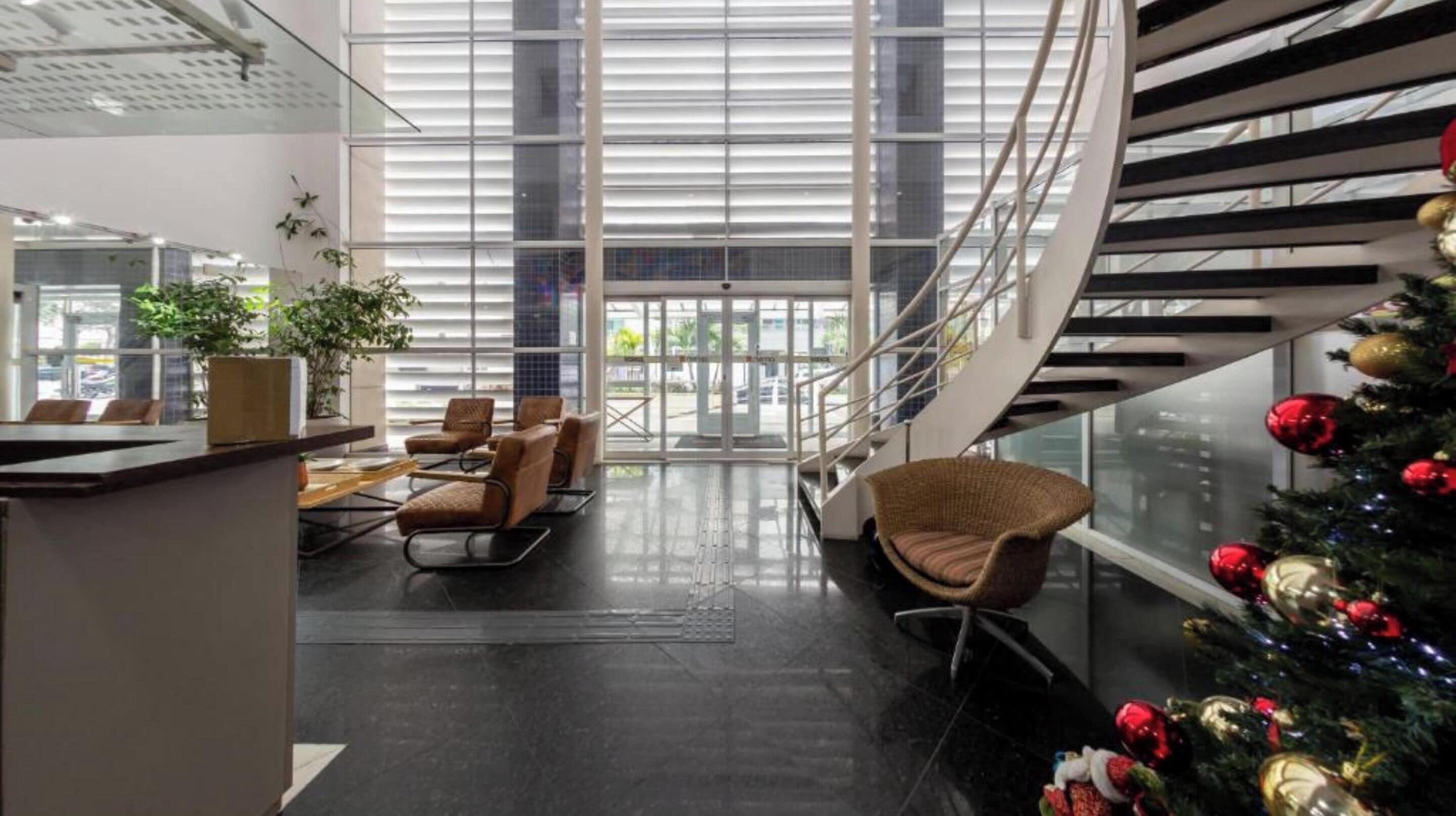Een moderne lobby met een glazen trap, een zithoek en een kerstboom.