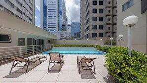 A rooftop pool area with lounge chairs, a small pool, and high-rise buildings in the background. - St. Charbel by Charlie (São Paulo)