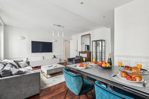 Una sala moderna con sofá, reposapiés y comedor con desayunador.