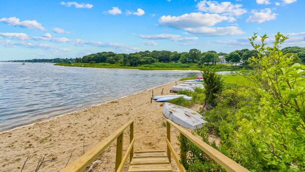 A beach with a wooden walkway leading to a row of surfboards. - Falmouth Family Home: Beach, Fire Pit & Games! (Falmouth)