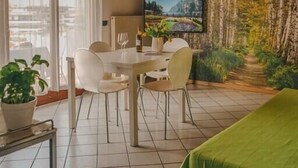 Een eetruimte met een houten plafond, een televisie aan de muur en uitzicht op de omgeving door grote ramen.