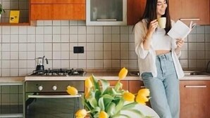 Een moderne keuken met houten kastjes, een gasfornuis en een witte betegelde spatwand.