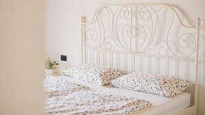 Een bed met een wit metalen hoofdeinde en bloemenbedrukking.