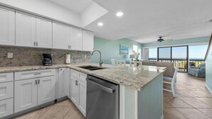 A modern kitchen with white cabinets, granite countertops, and a dishwasher. - Island House I205: Oceanfront, steps to pool, budget friendly (Saint Augustine)