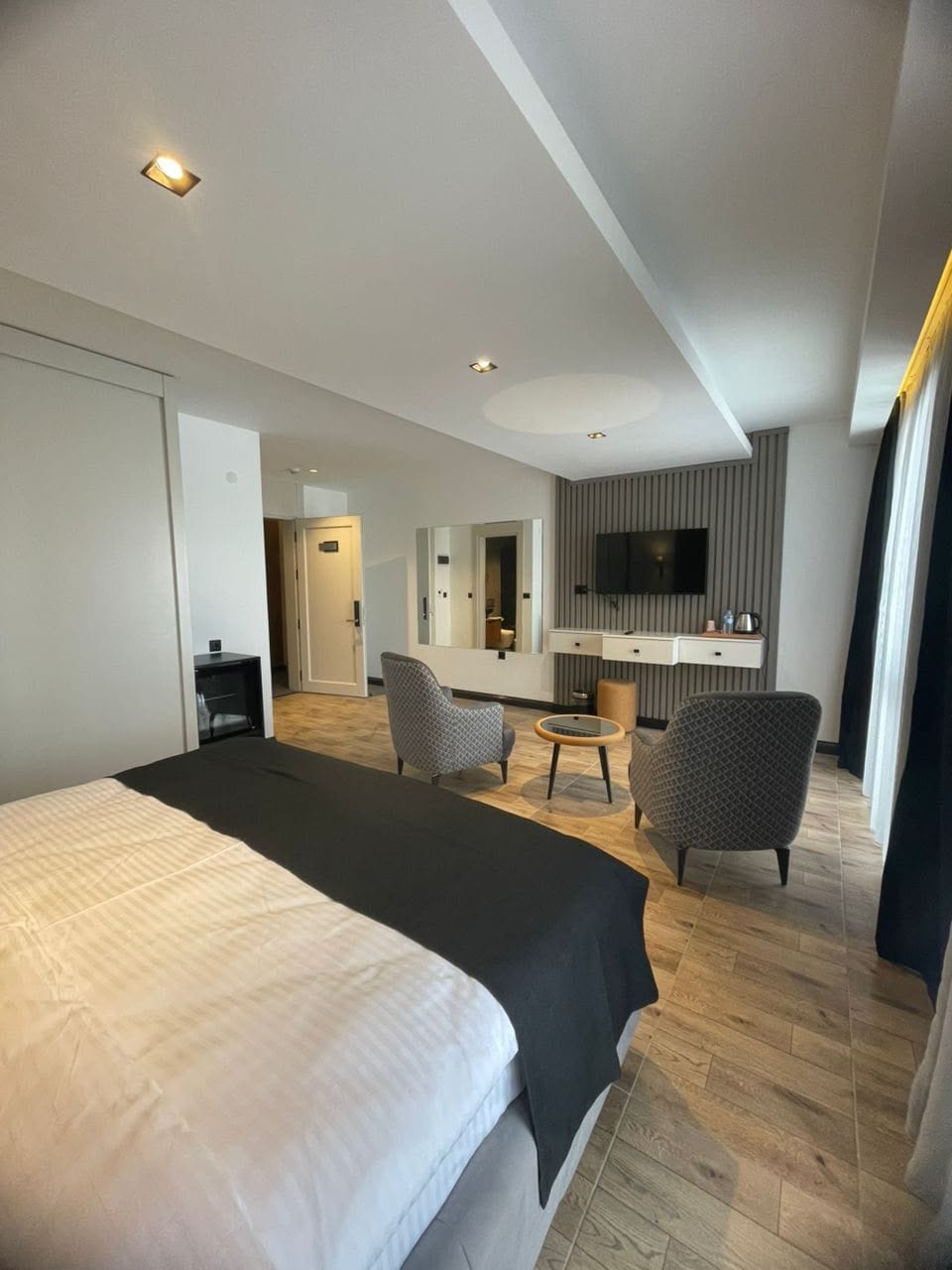 Una habitación de hotel moderna con una cama grande, un escritorio, una silla y un televisor.