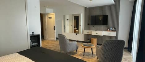 A modern hotel room with a large bed, a desk, a chair, and a television.