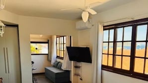 Une chambre d’hôtel avec un lit, un ventilateur de plafond, une télévision et une vue sur le paysage désertique.