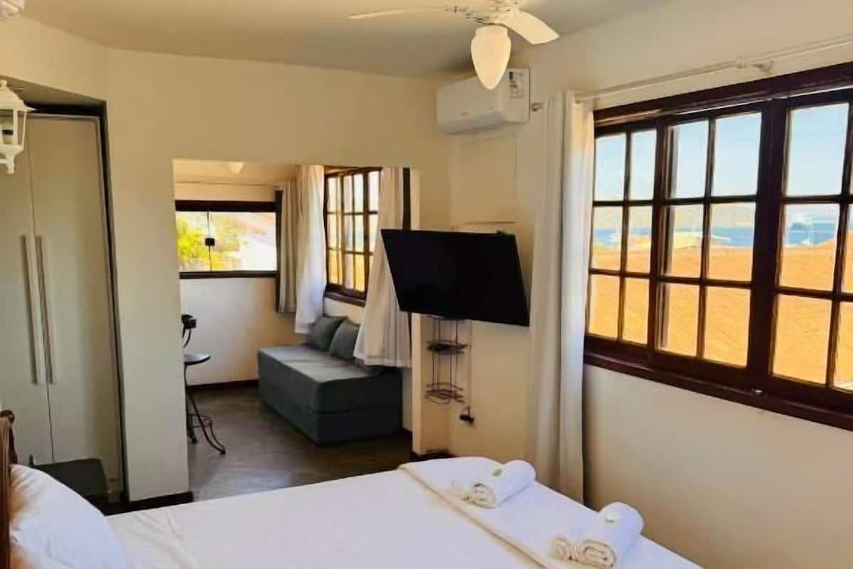 A hotel room with a bed, a ceiling fan, a TV, and a view of the desert landscape.