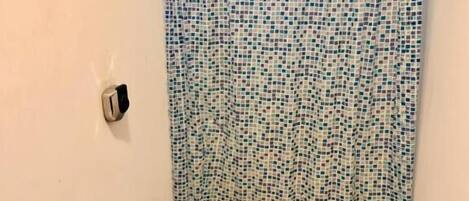 Un baño pequeño con inodoro, cortina de ducha y soporte para papel higiénico.