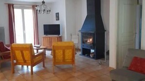 Een woonkamer met een open haard, een televisie en een bank.
