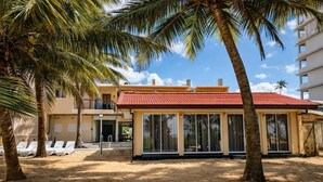 A beachside building with a red roof, large windows, and palm trees. - Lankahuts (Negombo)