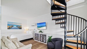 Un salon moderne avec un escalier en colimaçon, un canapé, une petite table et un meuble contenant des objets décoratifs.