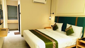 A hotel room with a bed, bedside table, and an air conditioning unit on the wall. - Kubo by Convivial Hotels (Raipur)