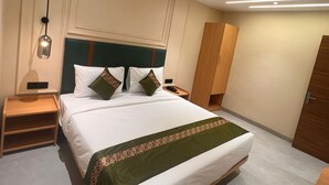 A hotel room with a large bed, a nightstand, a wardrobe, and a ceiling fan. - Kubo by Convivial Hotels (Raipur)