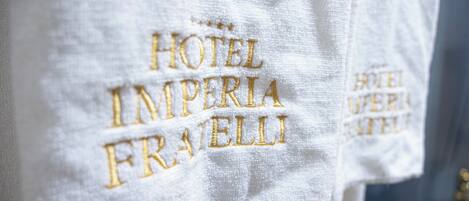 Una toalla blanca con el bordado 'HOTEL IMPERIA FRANZELLI' en dorado.