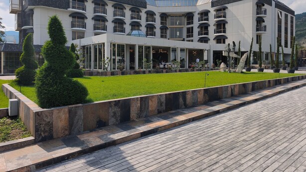 A multi-story hotel with a modern architectural design, featuring balconies, large windows, and a well-maintained lawn. - Hotel Imperia Fratelli (Sliven)