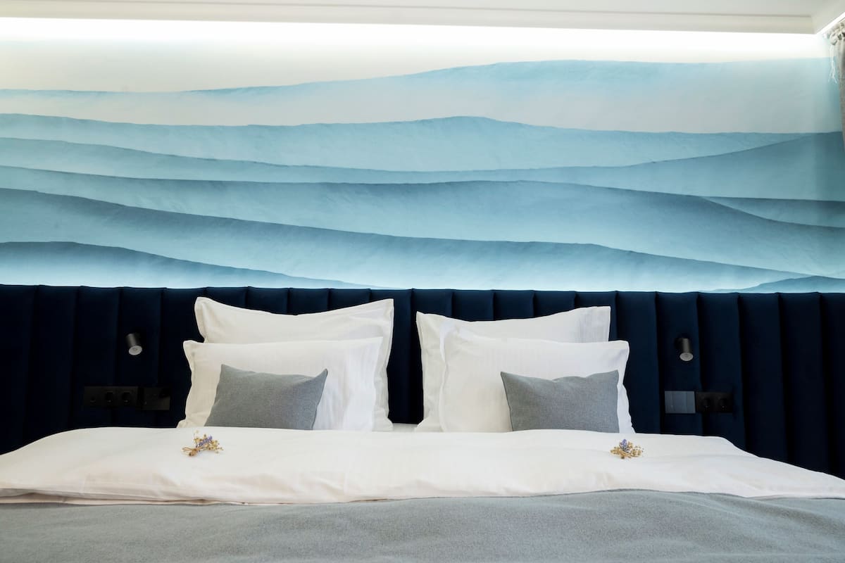 A bed with a dark headboard, white bedding, and decorative pillows.