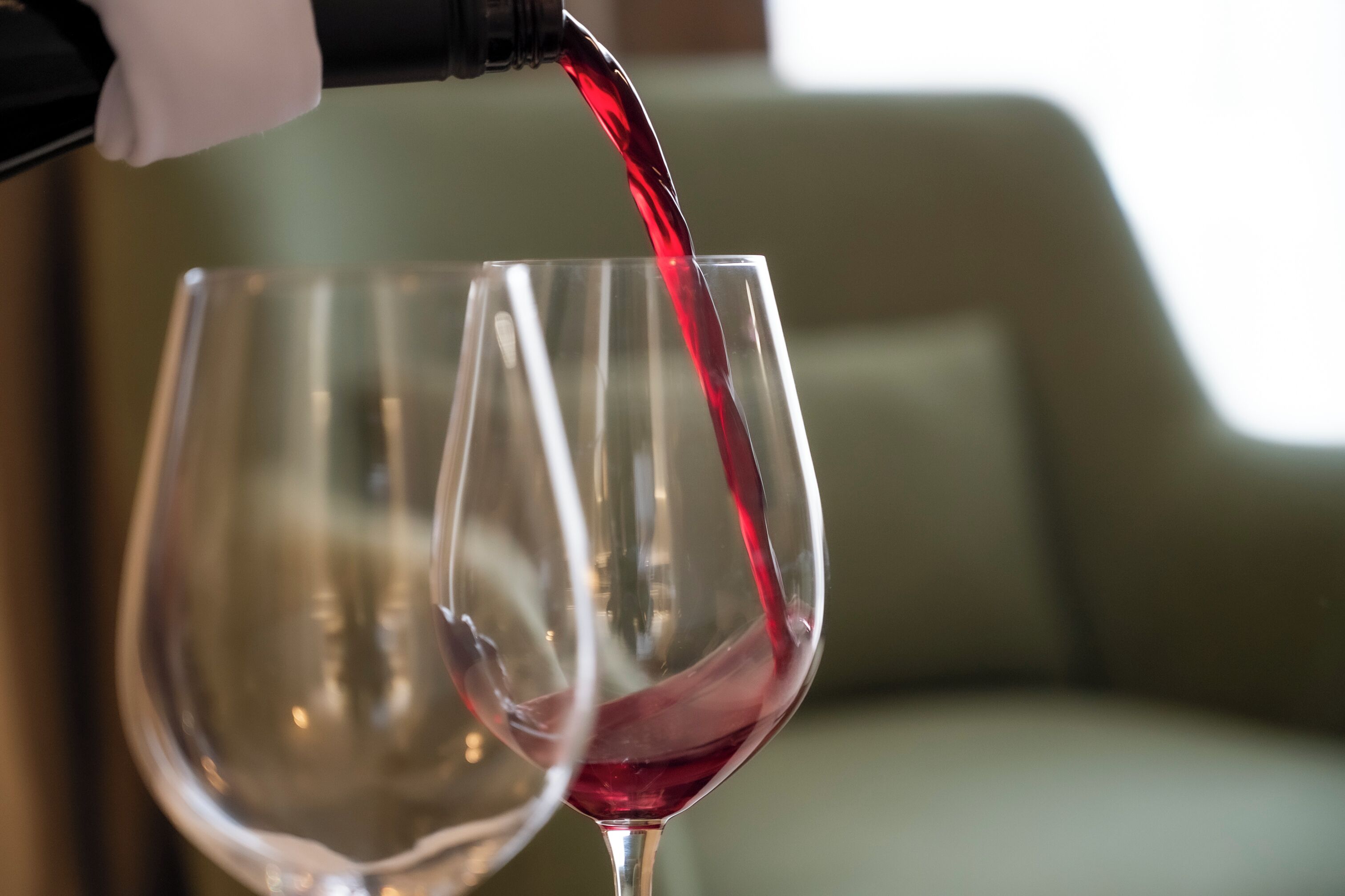 A wine glass being filled with red wine.