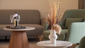 A round table with a vase of dried plants, a wine glass, and a bottle on a small stool. - Hotel Imperia Fratelli (Sliven)