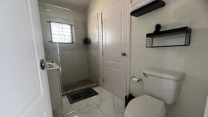 A bathroom with a toilet, a shower, and a sink. - Charming 2 Bedroom Home in Phoenix Park Village (Portmore)