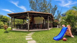 Eine überdachte Terrasse im Freien mit Essbereich, einer Rutsche und einem Gartenweg.