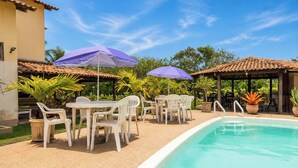 Ein Poolbereich mit Sitzgelegenheiten, Sonnenschirmen und einem Pool.