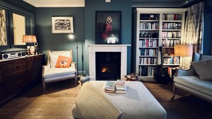 Un salon chaleureux avec une cheminée, une bibliothèque et un coin salon confortable.