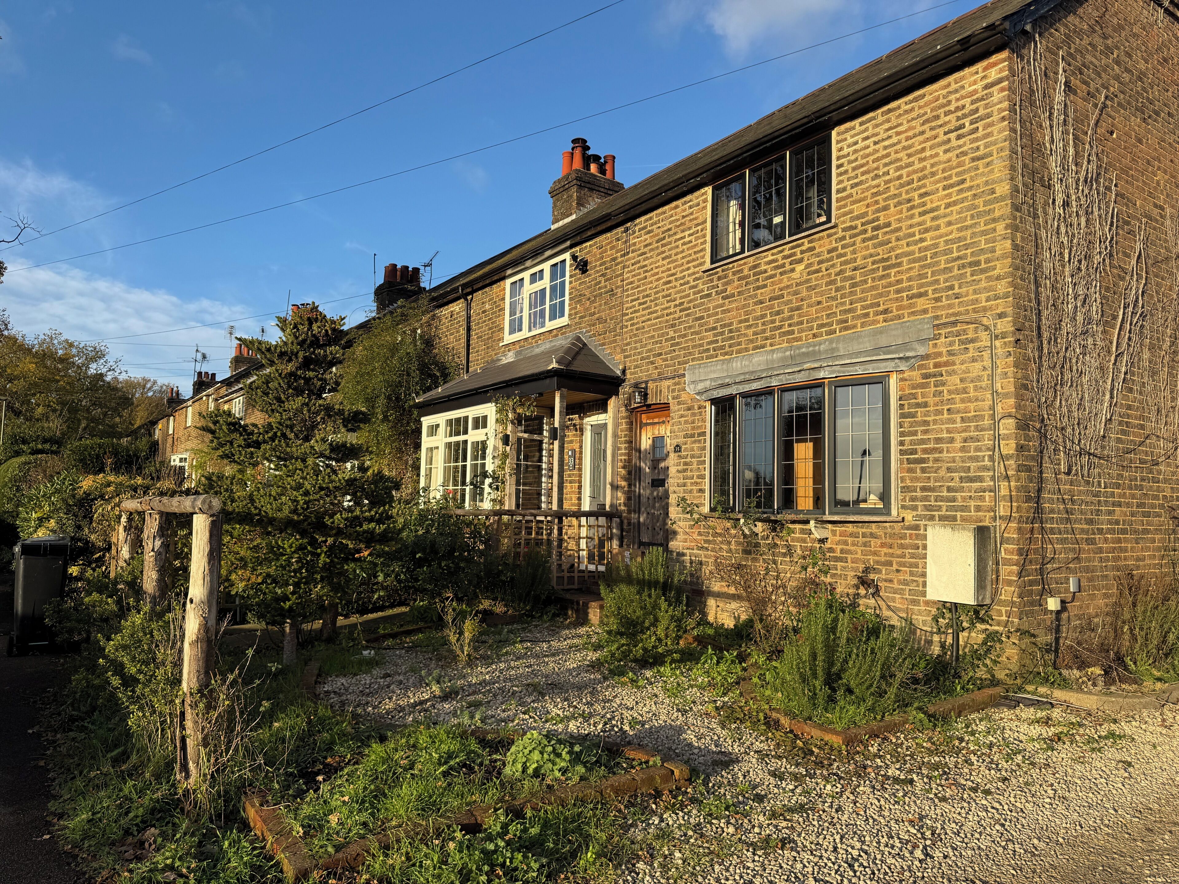 A brick house with a garden, a wooden fence, and a gravel path.