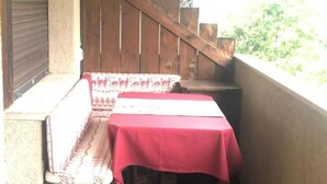 A balcony with a wooden staircase, a bench, and a table covered with a red tablecloth. - Apartment in San Vito di Cadore, Cortina 10 minutes away (San Vito di Cadore)