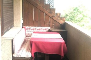 A balcony with a wooden staircase, a bench, and a table covered with a red tablecloth. - Apartment in San Vito di Cadore, Cortina 10 minutes away (San Vito di Cadore)