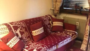 A red sofa with patterned cushions, a window with curtains, and a radiator. - Apartment in San Vito di Cadore, Cortina 10 minutes away (San Vito di Cadore)