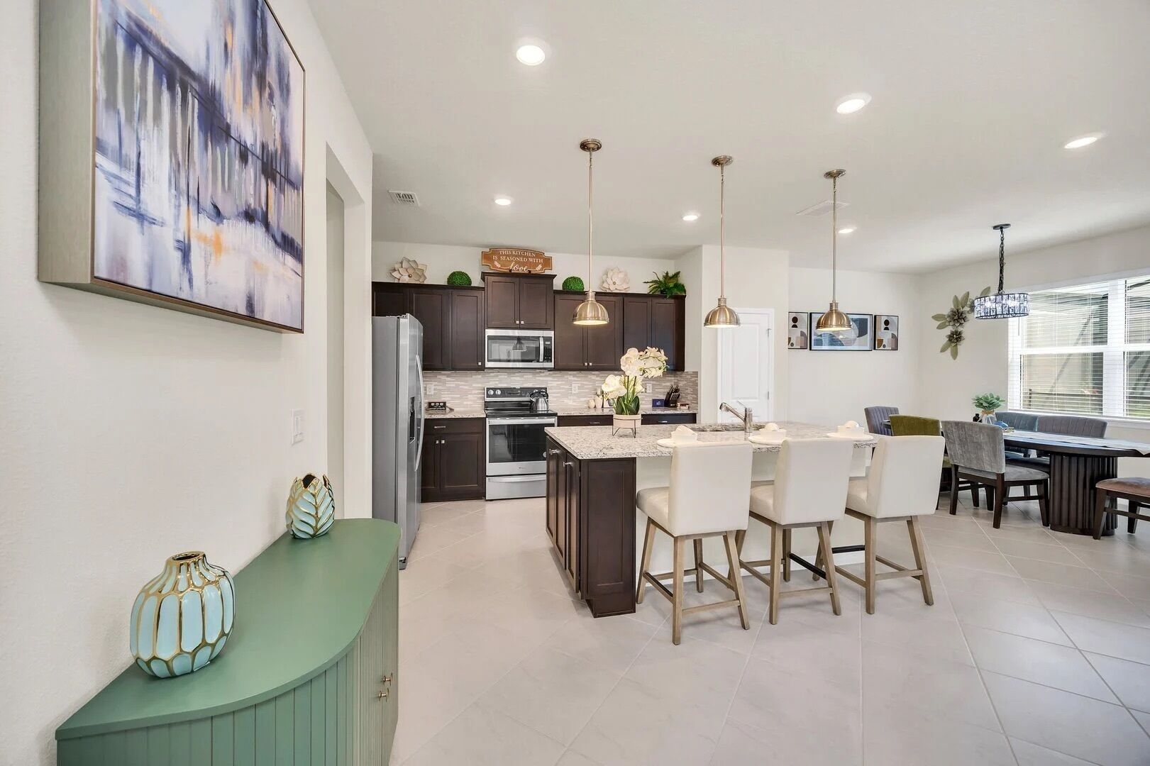 A modern kitchen with dark cabinets, stainless steel appliances, and a central island with bar stools.