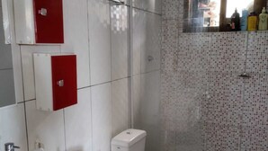 A bathroom with a white sink, red cabinets, a toilet, and a shower area. - Pink House Beach and Relaxation (Balneário Arroio do Silva)