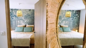 Une chambre à coucher avec un lit, un miroir et un mur orné d’un motif texturé.