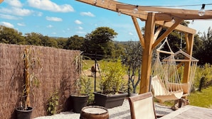 Une terrasse extérieure avec des meubles en bois, des guirlandes lumineuses et des plantes en pot.