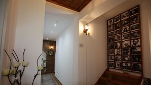 En hall med en trätrappa, en fotovägg och en väggmonterad lampa.