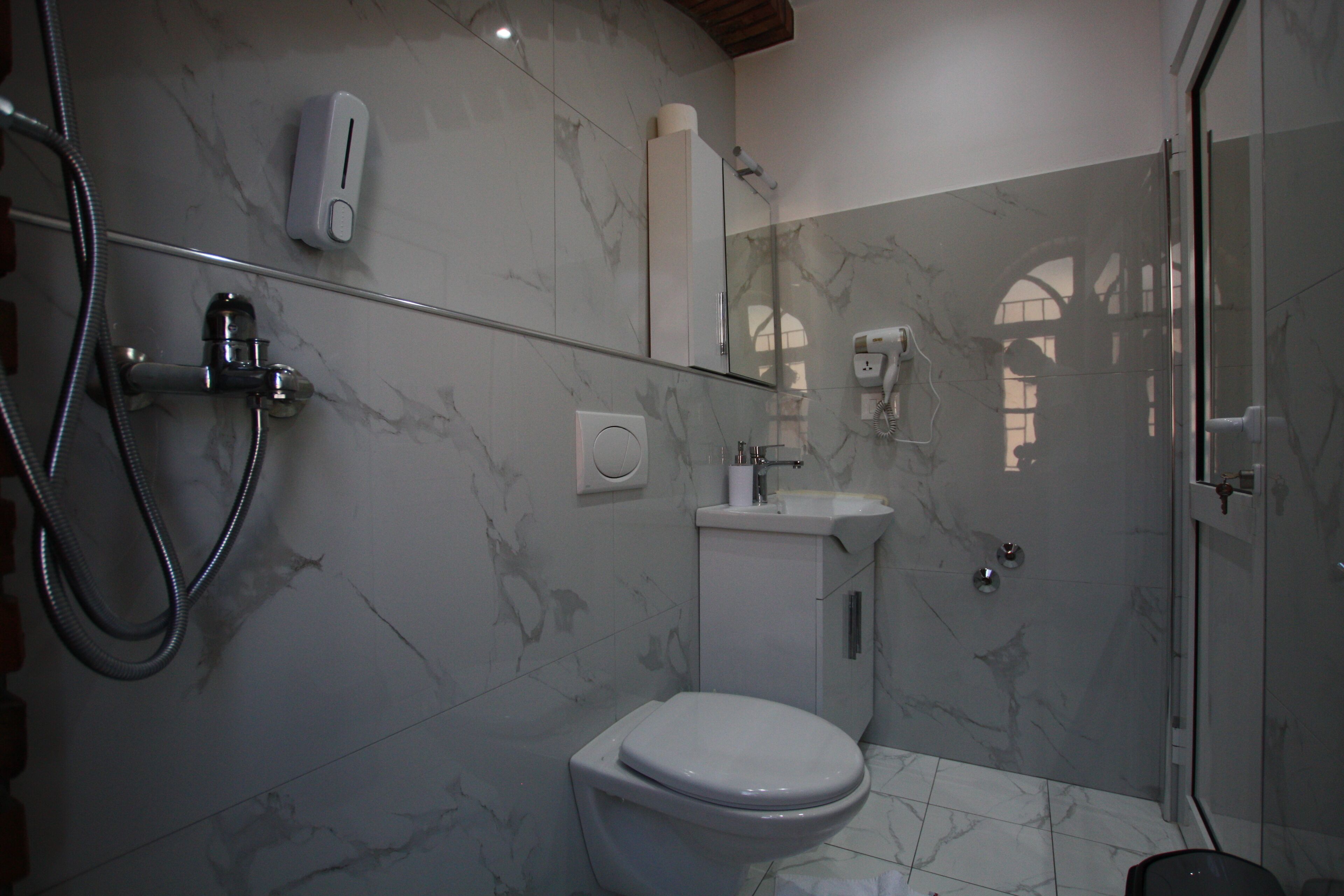A modern bathroom with a glass shower enclosure, a toilet, and a sink.
