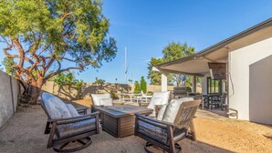 An outdoor patio with a dining table and chairs, surrounded by a gravel area and a tree. - NEW |The Pembrook @ Shaw Butte | Pool + Gameroom (Scottsdale)