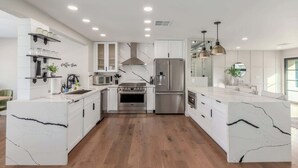 A modern kitchen with white cabinetry, stainless steel appliances, and a marble island. - NEW |The Pembrook @ Shaw Butte | Pool + Gameroom (Scottsdale)