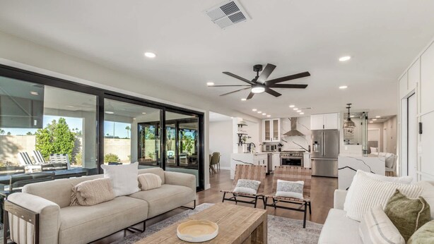 A modern living room with a sofa, coffee table, and chairs. There is a kitchen area with appliances and a dining area with chairs. - NEW |The Pembrook @ Shaw Butte | Pool + Gameroom (Scottsdale)
