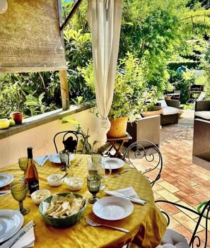 An outdoor dining area with a table set for two, surrounded by potted plants and wicker furniture. - Spacious 4-room apartment House with a garden and free... Parking Near Downtown   (Firenze)