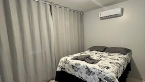 Quarto com cama, cortinas, ar condicionado e tapete.