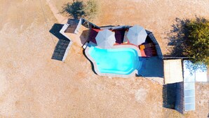 An aerial view of a swimming pool area with a rectangular pool, adjacent covered seating area, and a small adjacent structure. - Mozhi Bushcamp  (Kafue National Park)