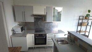 A modern kitchen with white cabinets, stainless steel appliances, and a tiled floor. - Studio de provence au coeur du Lubéron 33m2 pets welcome. (Cavaillon)