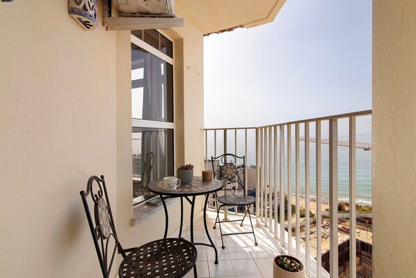 A balcony with two chairs, a table, and a potted plant. - Apt. 'Camões 11 D' with Sea View, Wi-Fi, Air Conditioning and Pool (Armação de Pêra)