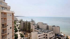 Ett bostadsområde vid kusten med flerfamiljshus, en strand och fri utsikt över havet.