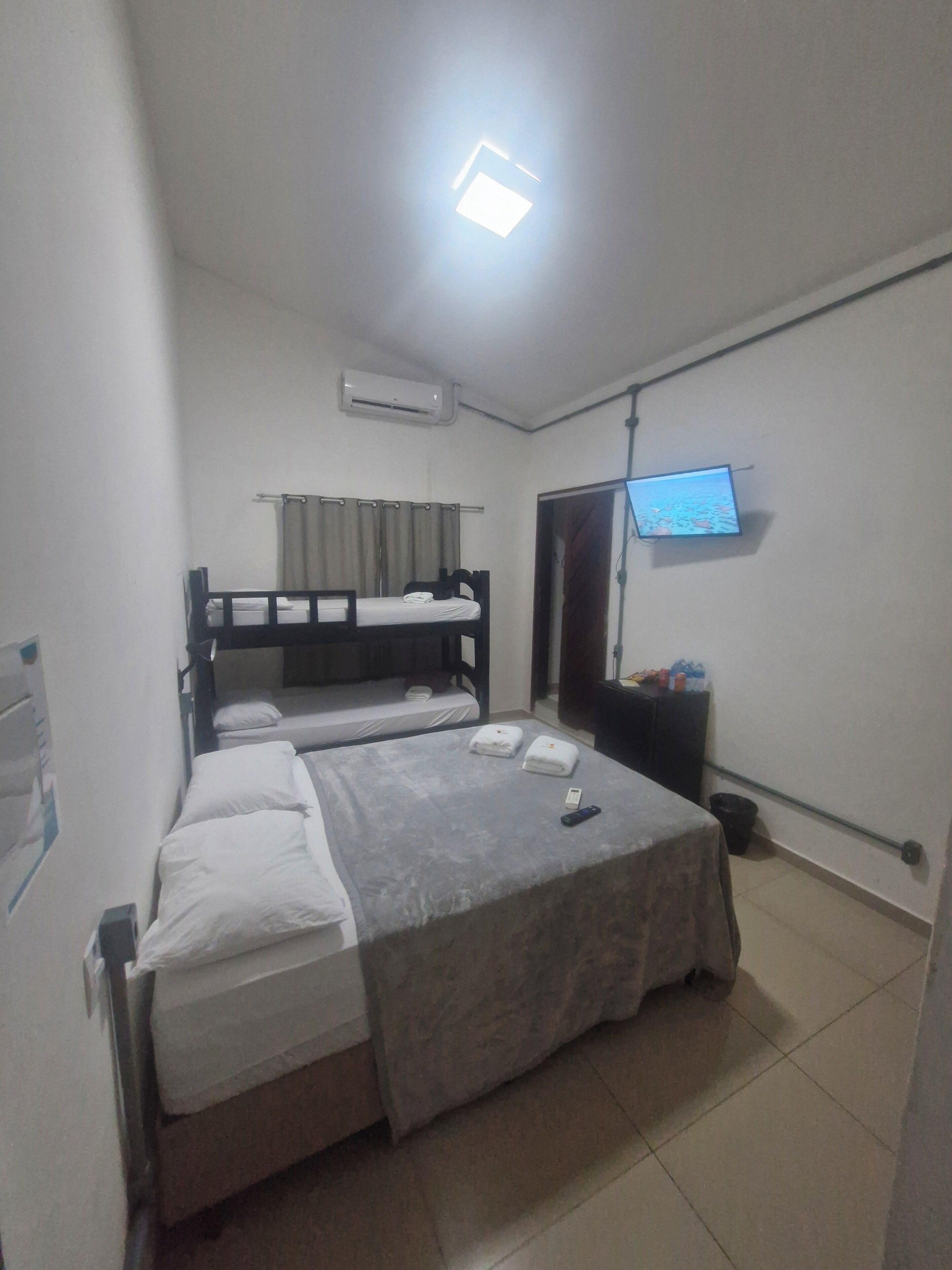 Una habitación con dos camas, un televisor montado en la pared y un equipo de aire acondicionado.