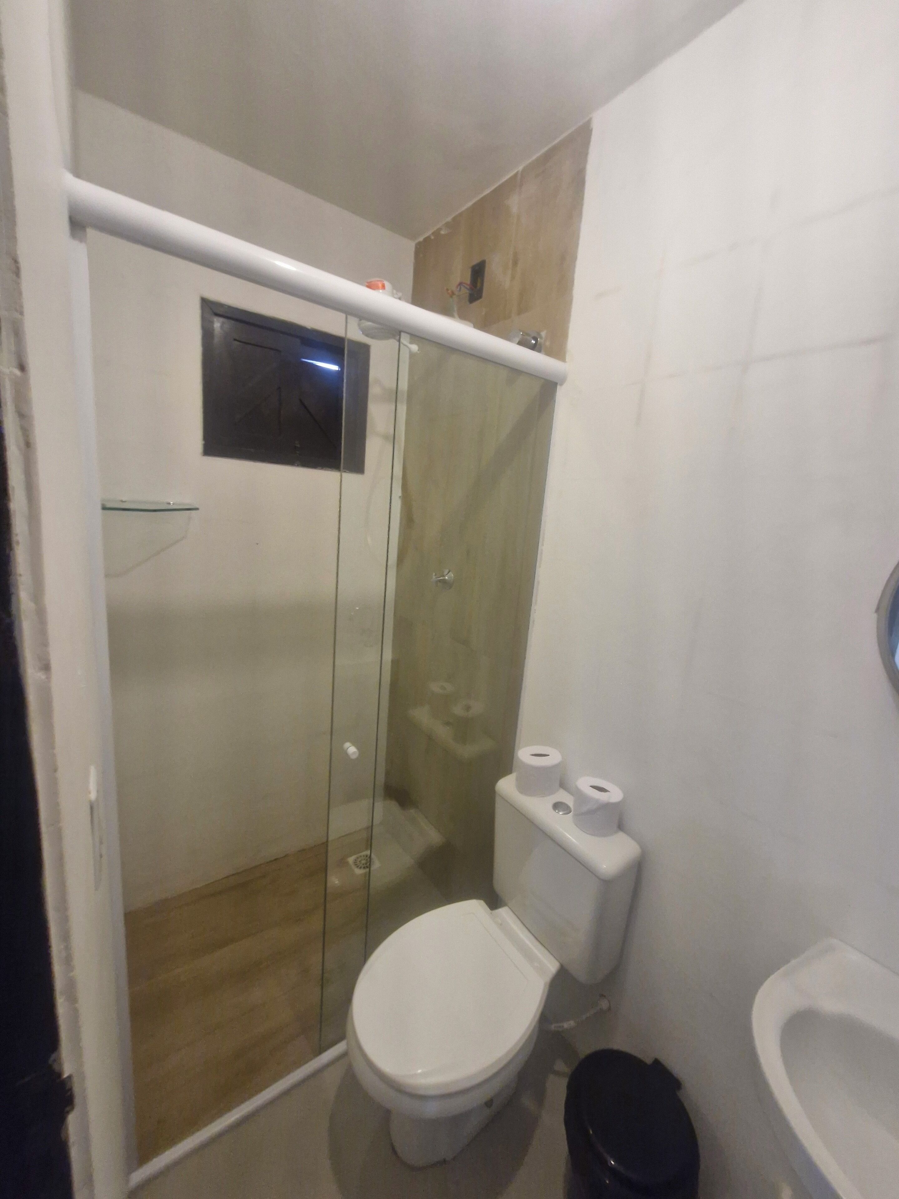 A small, compact bathroom with a glass-enclosed shower, a toilet, and a sink.